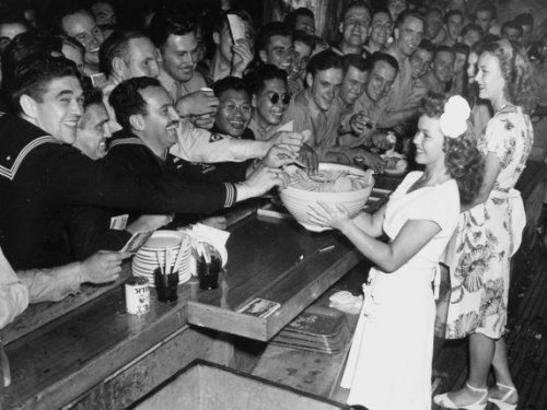 Film star Shirley Temple gives cookies to the soldiers at the Hollywood Canteen. Ca. 1942-45.